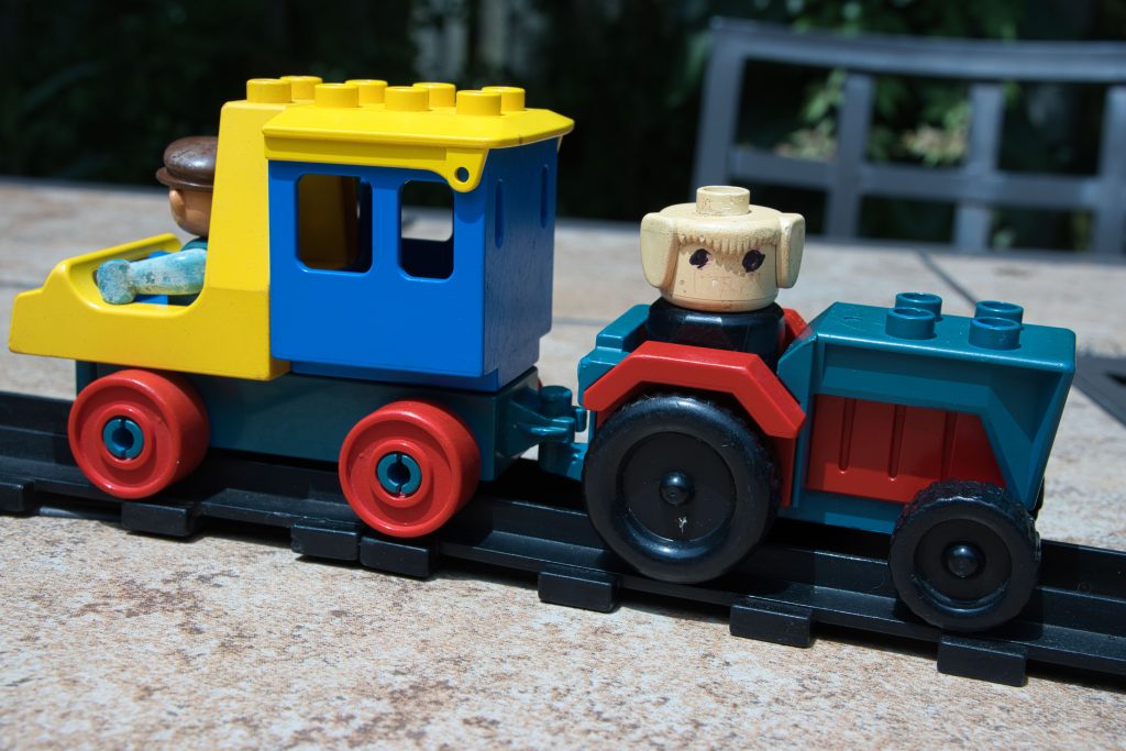 Duplo vehicles on original 1980s era "black" train track, including a dog driving a tractor and another figure driving a small van